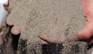 A grower holding a pile of fertilizer made from blended organic nutrients in their hands.